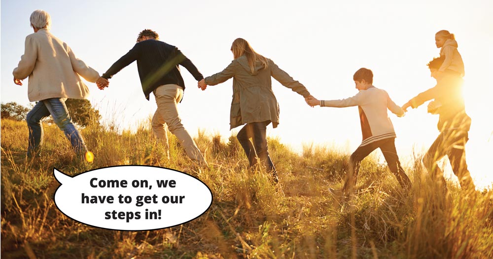 A family walks up a hill holding hands. Text says: Come on, we have to get our steps in!